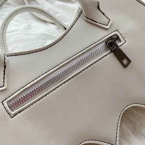 Close-up of metal zipper detail and handle attachment on white punk bat PU leather bag
