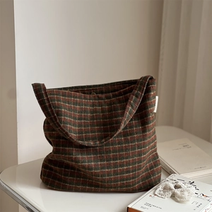 Close-up of vintage plaid wool tote bag with brown and green patterns on white table