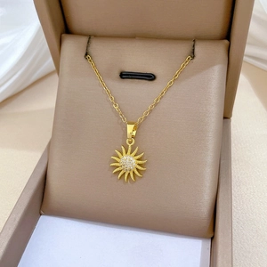 Detailed view of luxury gold sunburst pendant with sparkling crystals in premium gift box