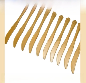 Close-up of golden plastic cake knives with serrated edges for holiday party supplies