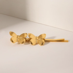 Détail de deux barrettes papillon dorées en acier inoxydable poli avec finition or 18K