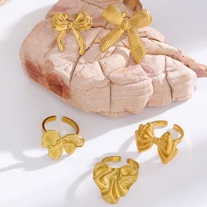 Detailed close-up of mixed bow design gold rings displayed on natural stone props