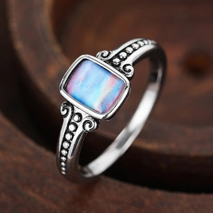 Macro shot of retro silver ring featuring a rectangle iridescent opal stone and floral carvings