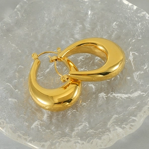 Close-up of thick gold-plated U-shaped earrings with a high-polished mirror finish