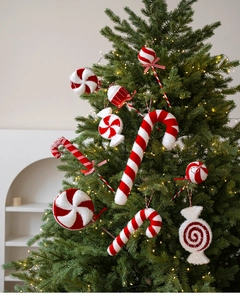Macro detail of red and white peppermint candy ornaments hanging on a lighted Xmas tree