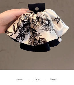 Detail of champagne floral satin scrunchie with single pearl pendant in soft natural light