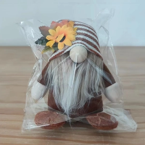 Detail of harvest gnome plush with sunflower and maple leaf in clear packaging
