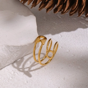 Minimalist gold paperclip safety pin wrap ring displayed on natural white rock background