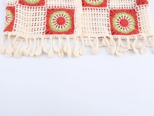 Close-up of crochet knit cardigan hem with granny square patterns and fringed tassels