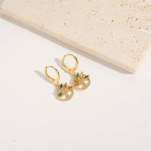 Macro shot of gold tree of life earrings with multicolored zircons on beige stone