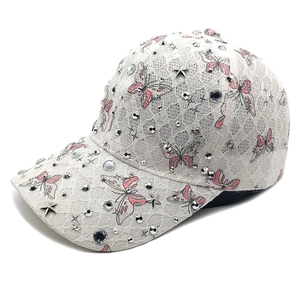 Detailansicht der weißen Spitzenkappe mit rosa Schmetterlingen, Strass und Sternnieten