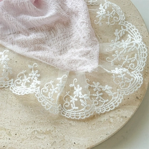 Close-up of pink seersucker fabric with exquisite white lace embroidery on a stone plate