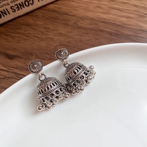 Detailed close-up of vintage silver Jhumka earrings with hollow carvings and beaded tassels