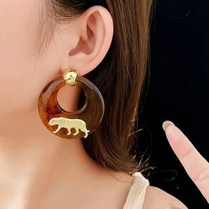 Close-up of tortoise shell resin hoop earring featuring a golden leopard motif decoration