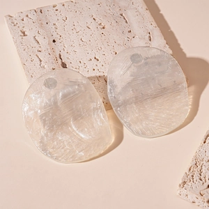 Detailed view of pearlescent resin irregular disc pendants on a textured stone base