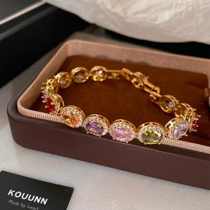 Luxurious gold bracelet with oval multi-color gemstones and pavé crystals on a gift box