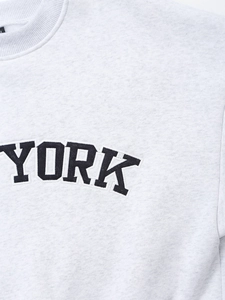 Close-up of YORK letter embroidery on light grey fleece sweatshirt with ribbed collar