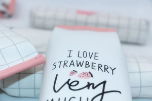Close-up of strawberry print PU leather pencil case with pink trim and grid pattern