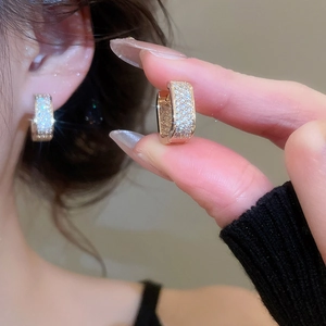 Close-up of sparkling rose gold hoop earrings with pavé set micro zircons on ear