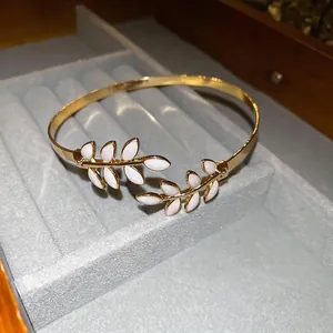 Gold-plated leaf-shaped open bangle featuring white enamel details and sparkling finish