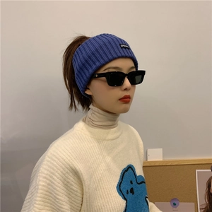 Close-up of a blue knitted sports headband styled with black rectangular sunglasses