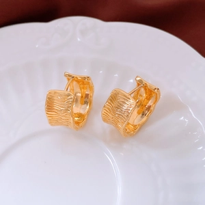Macro shot of 18K gold plated wide hoop earrings with unique irregular pleated textures