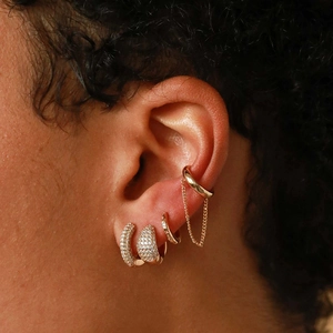 Close-up of gold ear cuff set with star zircons and delicate chain on model's ear