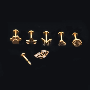 Detail view of golden G23 titanium piercing studs set with heart and butterfly shapes