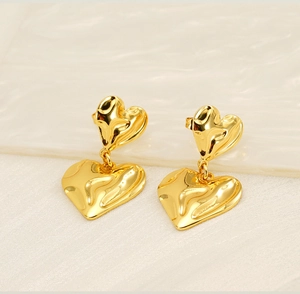Détail macro de boucles d'oreilles double cœur plaqué or 18K avec texture métal lave
