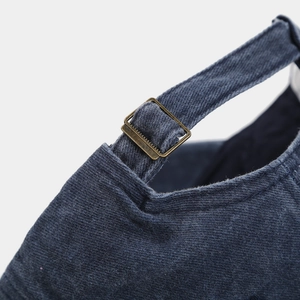 Detail of vintage bronze metal buckle and adjustable strap on navy denim baseball cap