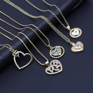 Macro shot of gold-plated heart necklaces with cubic zirconia, pearls and evil eye charms