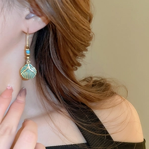 Detail of bohemian starfish shell earrings in vintage gold and green on a female model