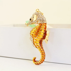 Golden seahorse keychain pendant with orange enamel and crystal rhinestones on a white box