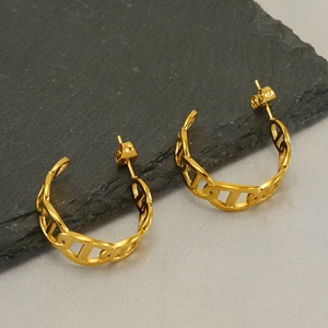 Detail view of gold chain link hoop earrings on dark grey stone with a high-shine finish