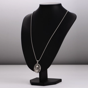 Vintage oval silver pendant with religious figure relief on a black mannequin