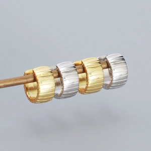 Macro shot of 925 sterling silver hoop earrings with textured irregular grooved surfaces