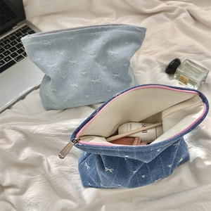 Close-up of denim cosmetic bags with white bow embroidery and durable zipper detail