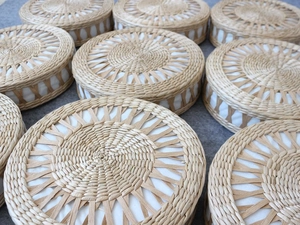 Close-up of stacked round handmade straw meditation cushions in natural grass color