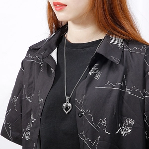 Gros plan du pendentif cœur en acier titane vintage avec détails crânes sur modèle