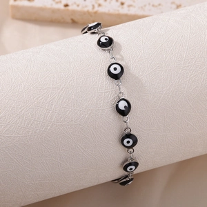 Detail of silver chain bracelet featuring black and white evil eye beads on a display