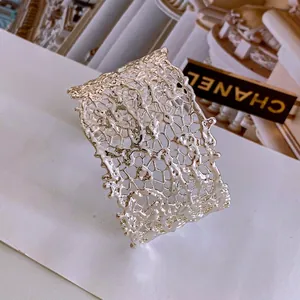 Modern silver open cuff bracelet featuring an intricate lava-textured hollow design