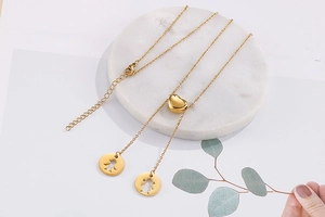 Détail du curseur cœur réglable et du collier en Y doré avec pendentifs ajourés