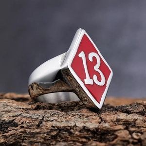 Macro shot of stainless steel ring featuring a red enamel diamond face and number 13