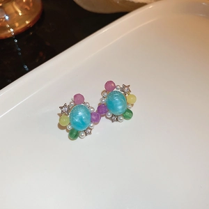 Détail de boucles d'oreilles fleurs en cristal coloré avec perles et étoiles