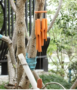 Close-up of natural bamboo wind chime tubes hanging from a tree branch in a garden