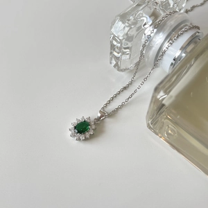 Detail of flower-shaped pendant with emerald green stone and white cubic zirconia