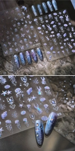 Macro detail of laser holographic nail stickers with jellyfish, starfish and butterfly motifs