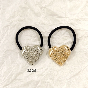 Detail of 3.5cm gold and silver hollow heart charms on black elastic hair ties