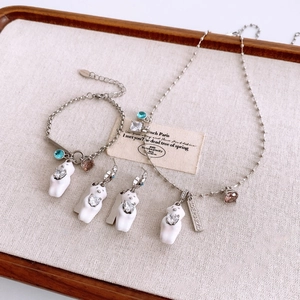Detail view of bear jewelry set with necklaces and bracelets on a textured wooden tray