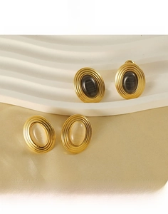 Close-up of vintage oval stainless steel earrings with natural stone inlay and texture